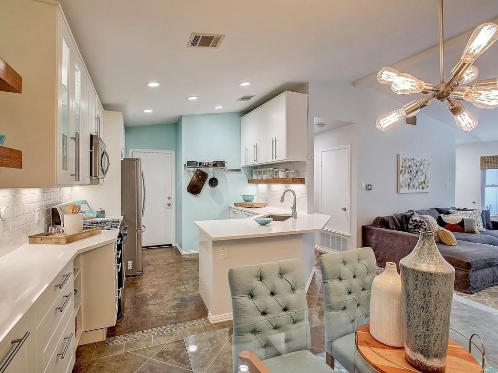 12909 Modena Trail Austin, TX 78729 - Photo 7 of 26 a large white kitchen with stainless steel appliances kitchen island granite countertop a sink and cabinets