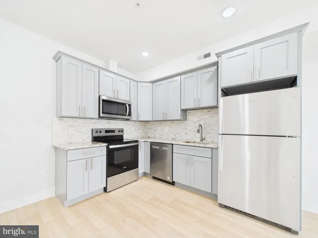 a kitchen with white cabinets and refrigerator