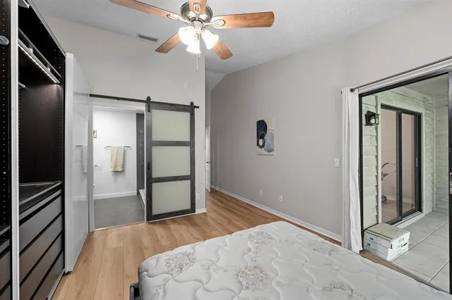 an empty room with wooden floor a ceiling fan and windows