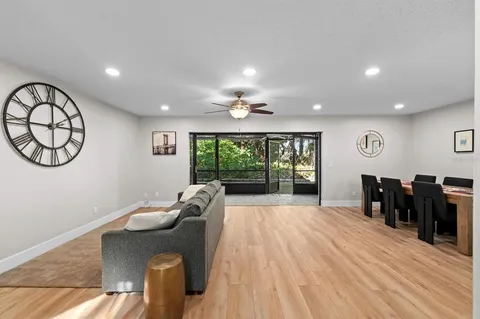 a living room with furniture a large window and wooden floor