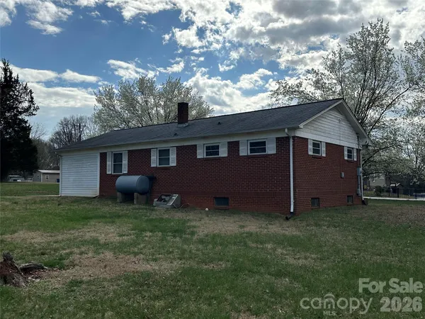 a view of a house with a yard tree and a fire pit