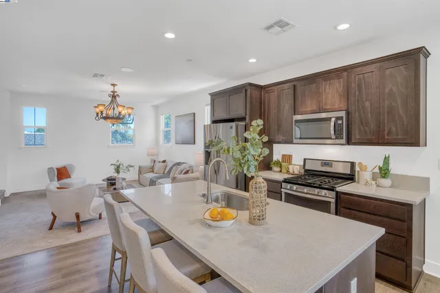 a kitchen with stainless steel appliances a table chairs and microwave