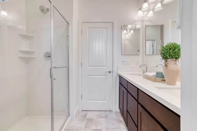 a bathroom with a granite countertop sink two mirror and shower