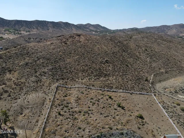 a view of a dry field with mountains in the background
