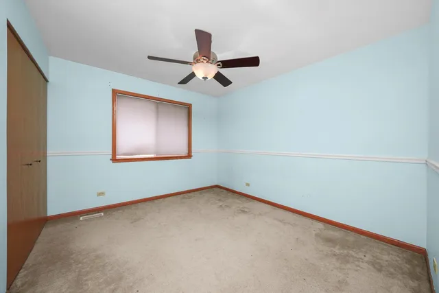 an empty room with a ceiling fan and a window