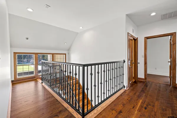 a view of a hallway with wooden floor and windows