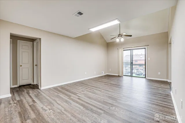 a view of an empty room with wooden floor and a window