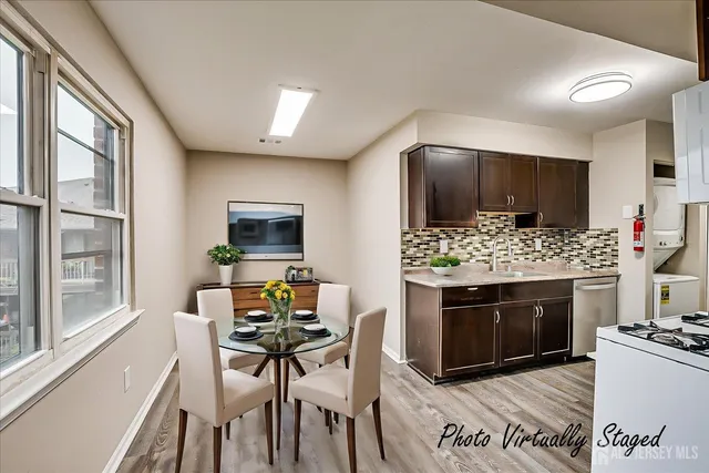 a living room with stainless steel appliances furniture a fireplace a flat screen tv and a large window