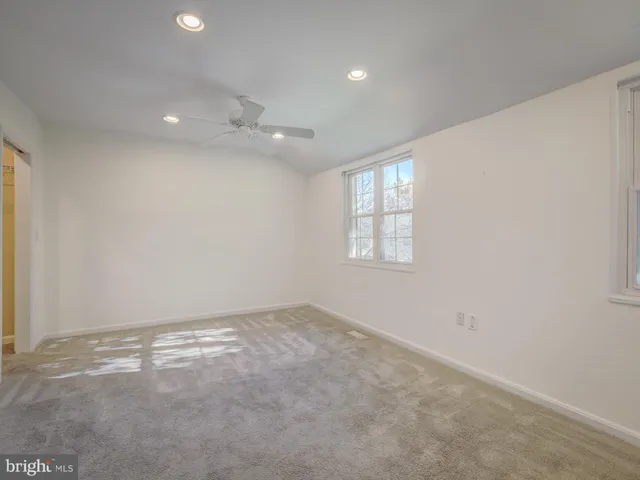 an empty room with windows and ceiling fan