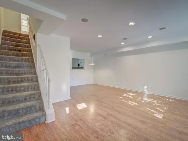 a view of an empty room with wooden floor and stairs