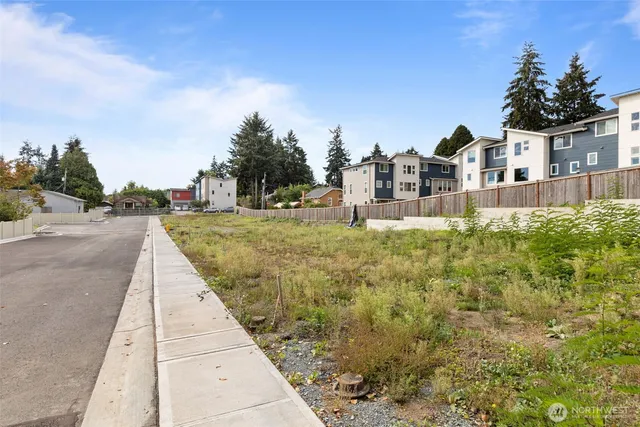 a view of a white house next to a yard with plants and trees