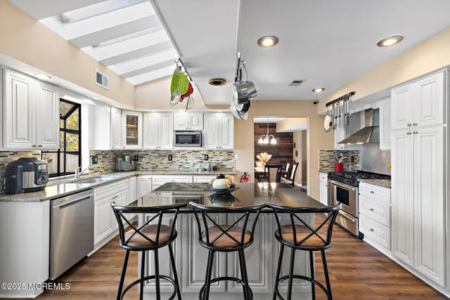 a kitchen with stainless steel appliances kitchen island granite countertop a table chairs and wooden cabinets