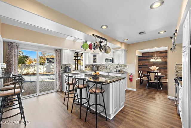 a kitchen with stainless steel appliances kitchen island granite countertop a table chairs and a stove