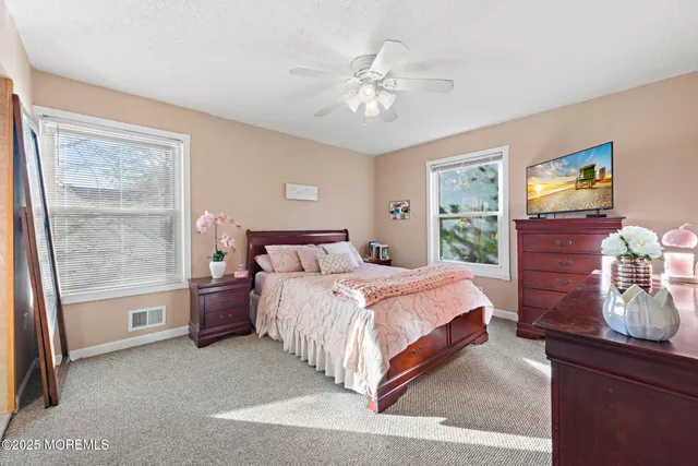 a bedroom with a large bed and a flat tv screen on dresser
