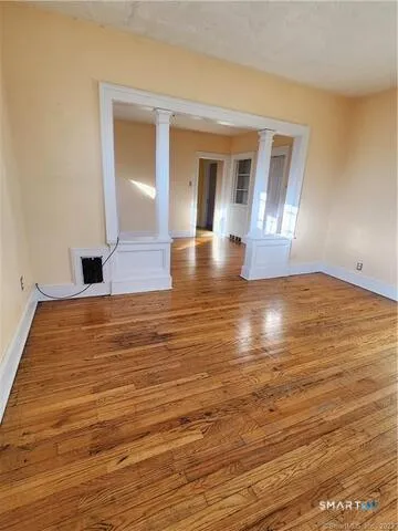 a view of empty room with wooden floor and fan