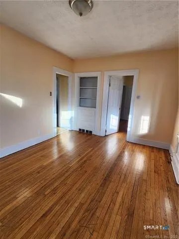 a view of a hallway with wooden floor and a bathroom