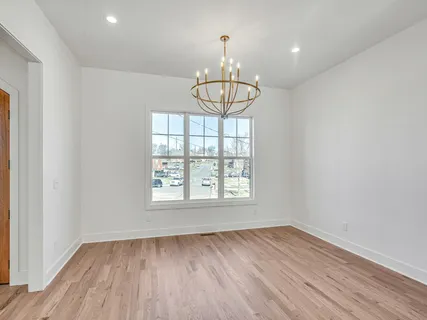an empty room with wooden floor chandelier and windows
