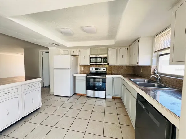 a kitchen with white cabinets a sink and a refrigerator