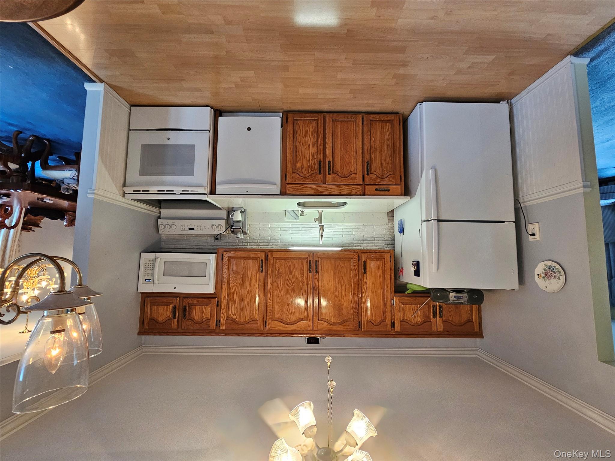 8 Laura Road Monroe, NY 10950 - Photo 3 of 12 Kitchen featuring a light countertops, white appliances, brown cabinetry, and backsplash