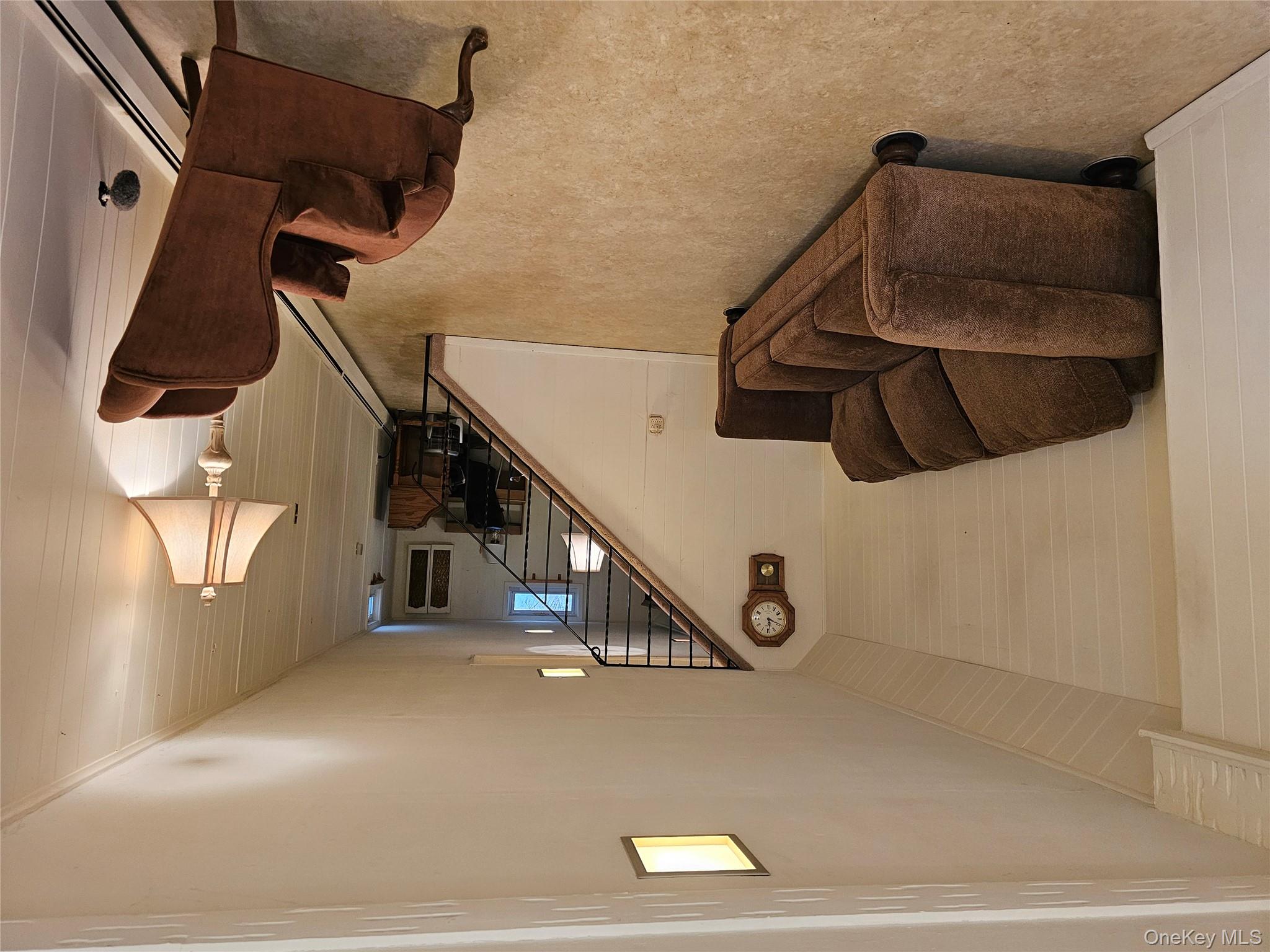 8 Laura Road Monroe, NY 10950 - Photo 4 of 12 Living room with a baseboard heating unit, stairway, and wood walls