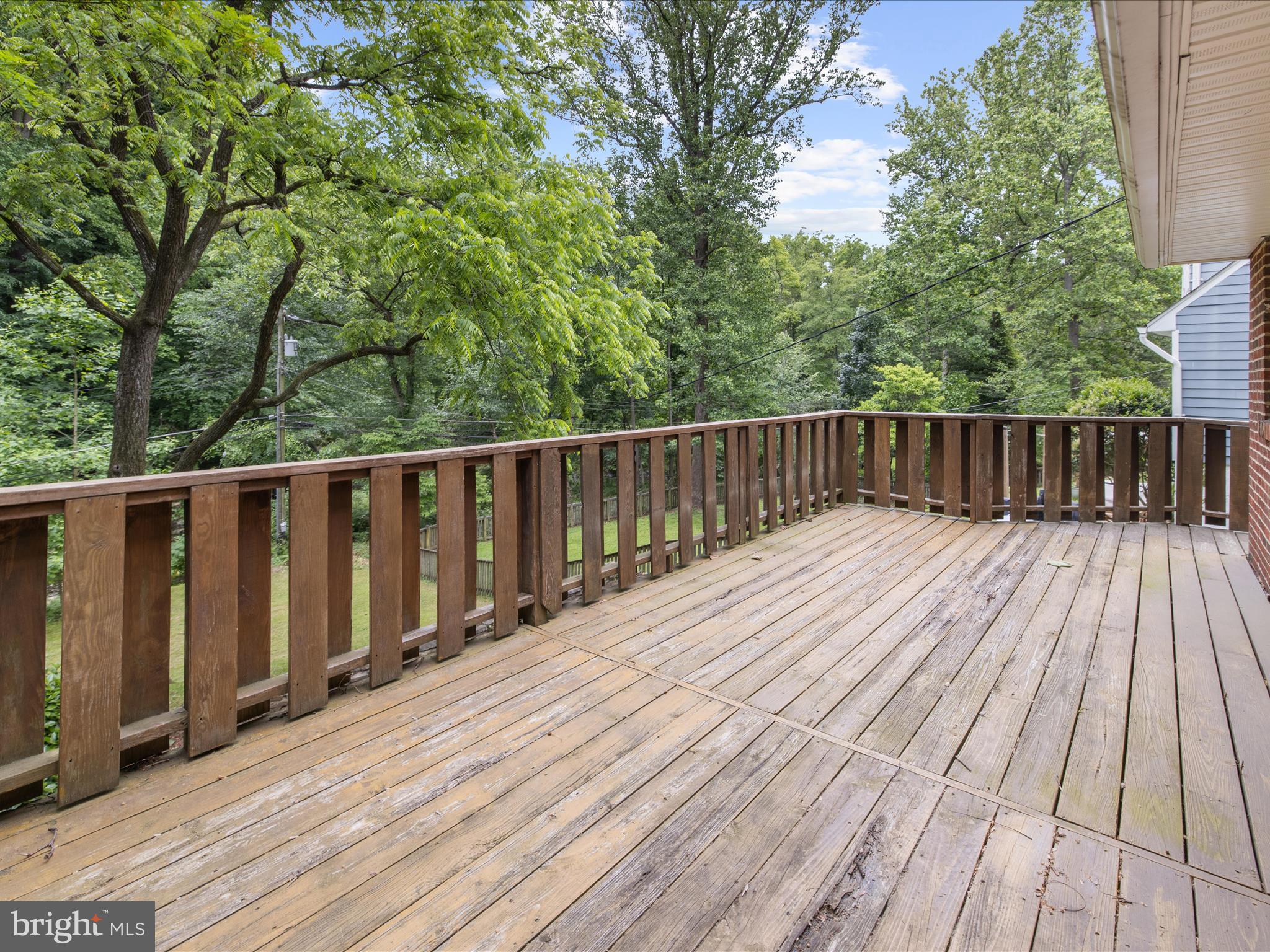 6748 Glenkirk Road Baltimore, MD 21239 - Photo 35 of 61 a balcony with wooden floor and trees in the back