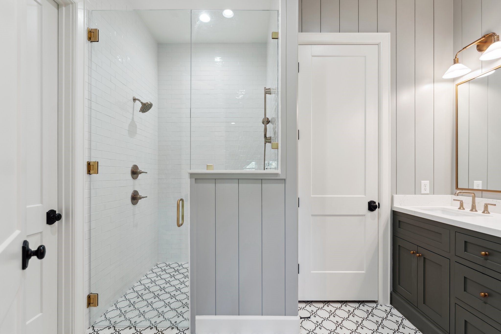 4052 Kuykendall Road Bellville, TX 77418 - Photo 12 of 40 Primary bath also features a sleek glass-enclosed shower with white subway tiles, elegant patterned floor tiles, and a double sink vanity with stylish lighting. The shiplap walls add a modern touch.