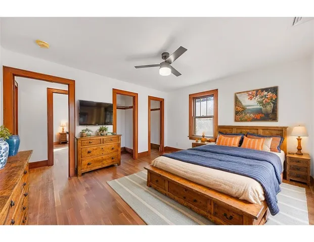 a bedroom with a bed and dresser with wooden floor