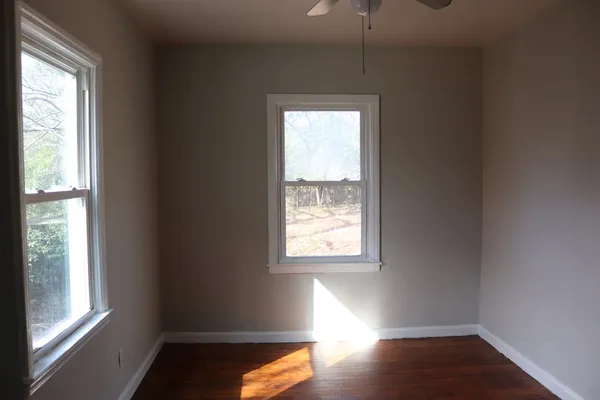 a view of an empty room with wooden floor and a window