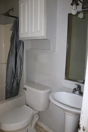 a white toilet sitting next to a bathroom sink and tub
