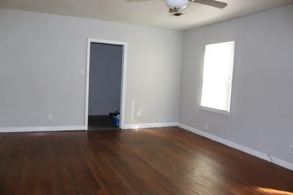 an empty room with wooden floor and windows