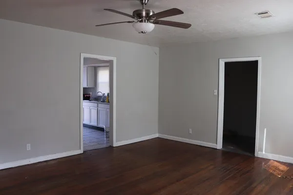 a view of empty room with wooden floor and fan