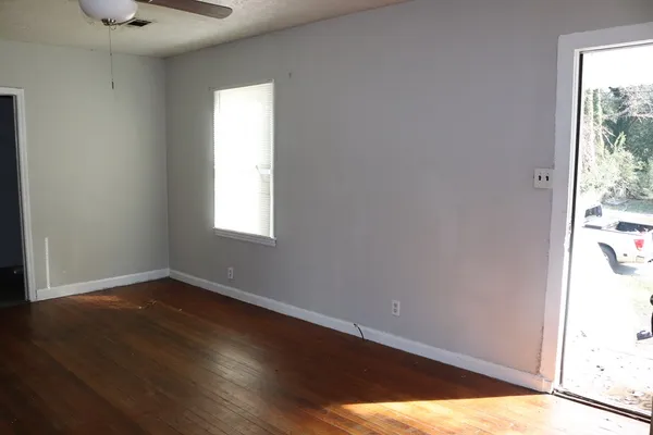 an empty room with wooden floor and windows