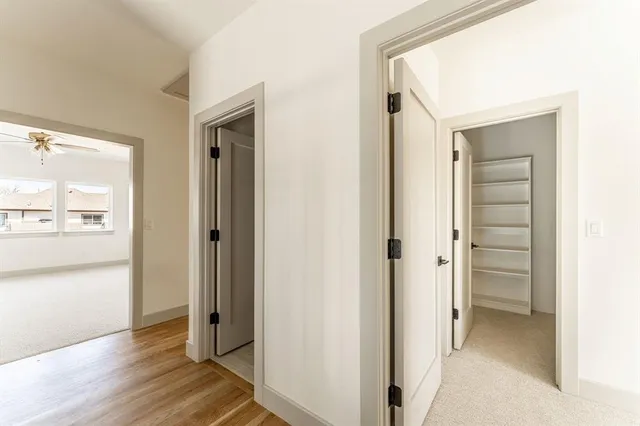 a view of a hallway with wooden floor windows and a living room