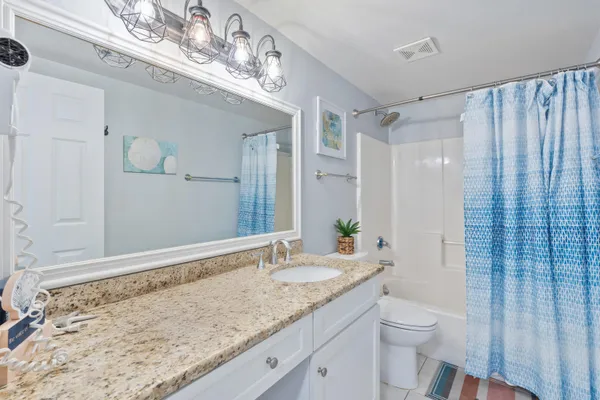 a bathroom with a granite countertop sink a toilet and shower