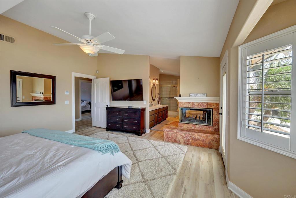 36485 Carney Road Valley Center, CA 92082 - Photo 29 of 75 a spacious bedroom with a large bed a flat tv screen and a chandelier