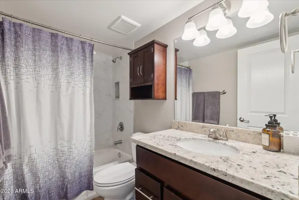 a bathroom with a granite countertop sink a toilet and a large mirror