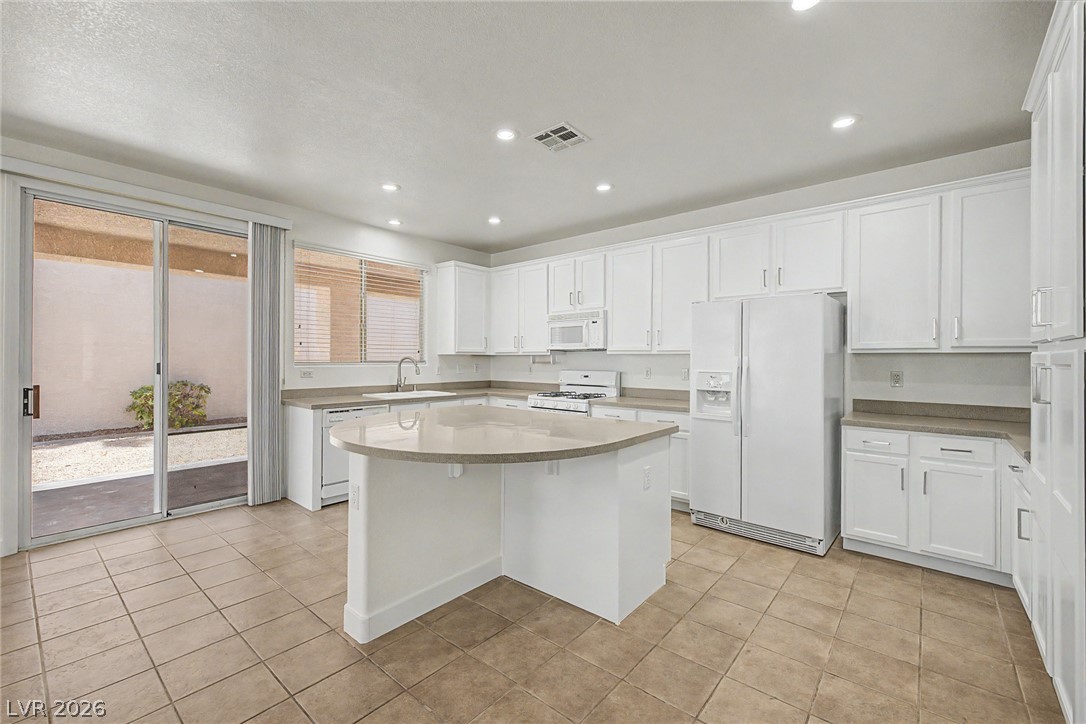 835 Entrada Ridge Avenue Henderson, NV 89012 - Photo 10 of 34 A well-lit kitchen with generous counter space, ample cabinetry, and an inviting island, perfect for culinary endeavors.