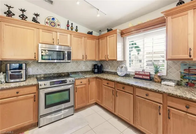 a kitchen with stainless steel appliances granite countertop white cabinets granite counter tops and a window