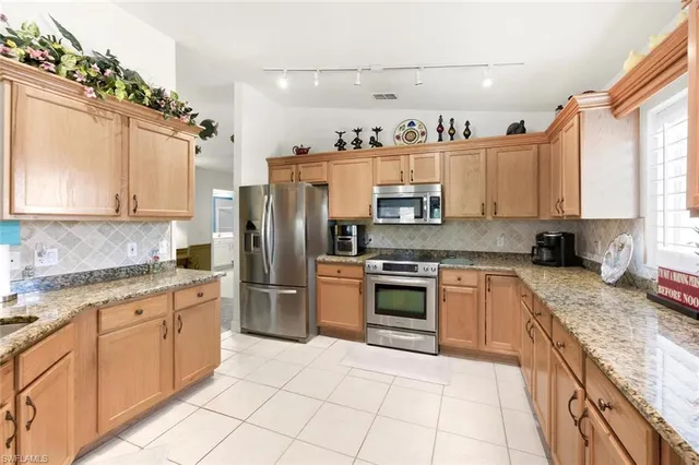 a kitchen with kitchen island granite countertop a sink counter top space appliances and cabinets