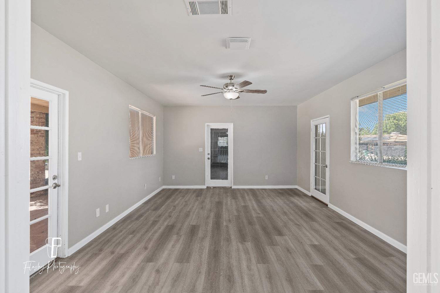 Undisclosed Address Bakersfield, CA 93308 - Photo 17 of 37 an empty room with wooden floor chandelier fan and windows