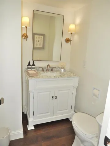 a bathroom with a granite countertop toilet sink and mirror