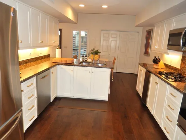 a kitchen with stainless steel appliances white cabinets and wooden floors