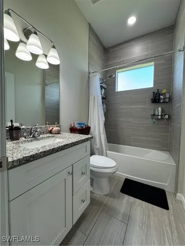 a bathroom with a granite countertop sink toilet a large mirror a bathtub and shower