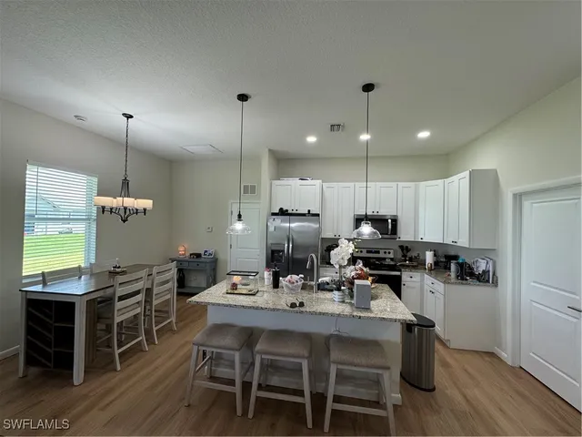 a kitchen with a dining table chairs and white cabinets