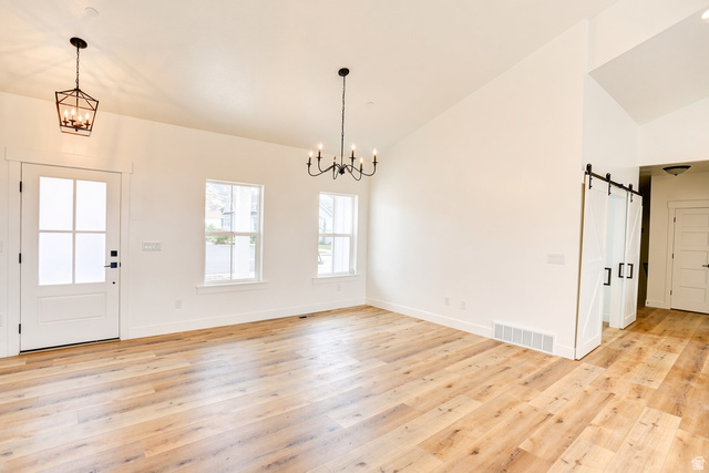 1257 North 1350th Street East Mapleton, UT 84664 - Photo 3 of 34 Vaulted ceilings, wood-finish flooring, white walls, multiple windows, and barn doors