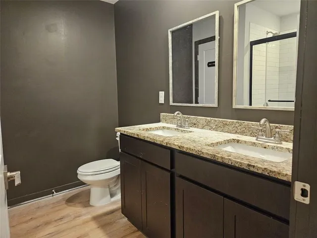 a bathroom with a granite countertop sink toilet and mirror