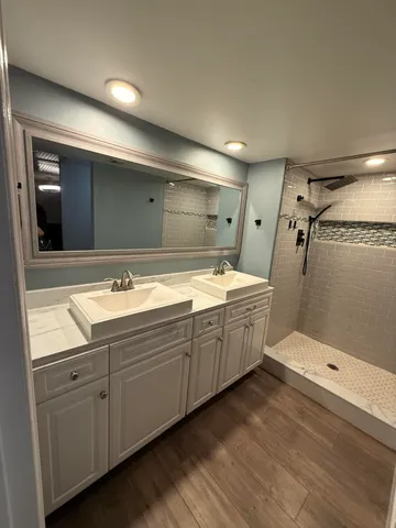 a bathroom with a double vanity sink and mirror with shower