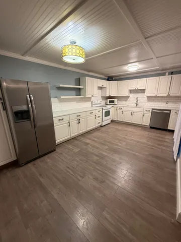 a view of a kitchen with stainless steel appliances wooden floor and a sink