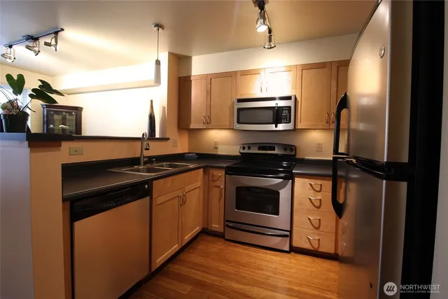 a kitchen with stainless steel appliances granite countertop a stove a sink and a microwave
