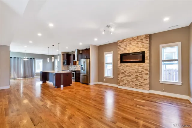 a view of kitchen with kitchen island granite countertop a stove top oven a sink and a island with wooden floor